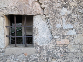 Fototapeta premium Old window with iron bars in stone wall