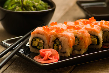Sushi and chuka seaweed salad with soy sauce on wooden table