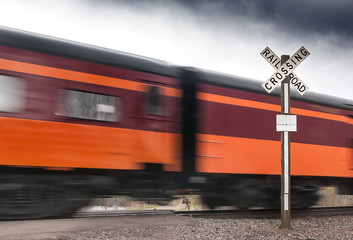 Orange & Maroon Passenger Car Flies by Railroad Crossing