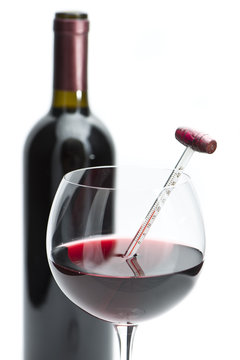 calice di vino con termometro e bottiglia su sfondo bianco