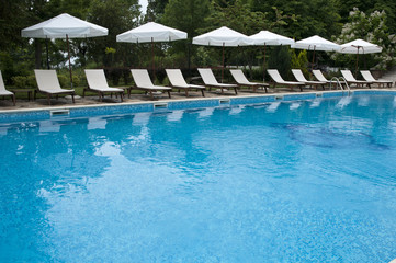 Blue swimming pool , sunbeds and umberalla for sunbath