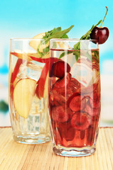 Glasses of fruit drinks with ice cubes on blue background