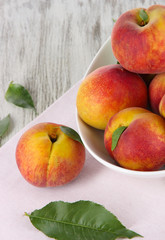 Peaches in plate on napkin on wooden table