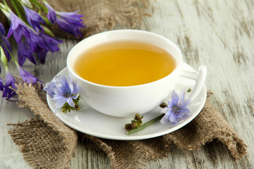 Cup of tea with chicory, on wooden background