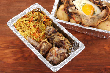 Food in boxes of foil on wooden background