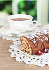 Sweet roll with cup of tea on table in room