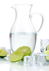 Glass pitcher of water with ice and lime isolated on white