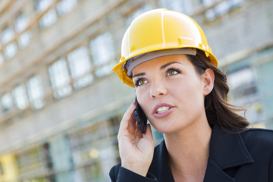 Young Female Contractor Wearing Hard Hat On Site Using Phone