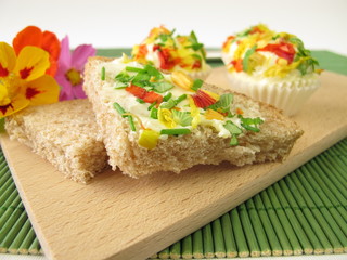 Kräuterbutter-Pralinen mit essbaren Blüten auf Brot