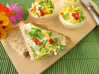 Kräuterbutter-Pralinen mit essbaren Blüten auf Brot