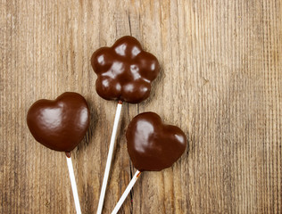 Chocolate cake pops in heart and flower shapes on wooden backgro