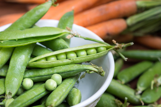 Pea pods in a bowl with carrots