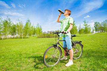 Young man on a bike drinking water