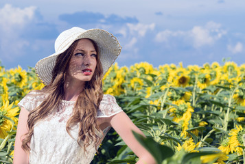 young woman on blooming sunflower field in summer