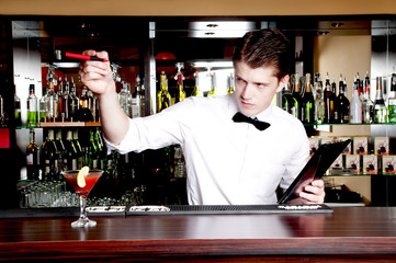 Young handsome bartender waiting an order.