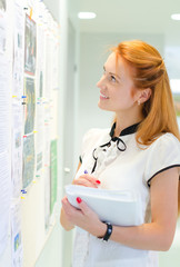 Young female student looking through job offers on board