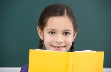 Happy schoolgirl.  Cheerful little schoolgirl looking out from t