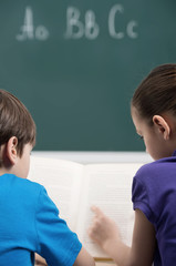 Studying together. Rear view of two little classmates reading a