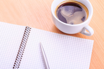 Open blank note book with coffee cup on table