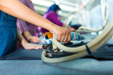 Indonesian worker with flat iron in textile factory