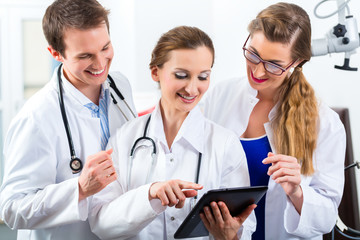 Team of young doctors in clinic with tablet computer