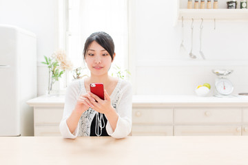 young asian woman using smart phone in the kitchen