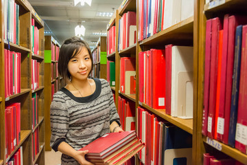 Thai college girl is holding stack of books .