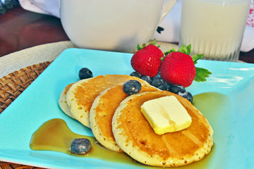 Breakfast of three pancakes, strawberries and blueberries