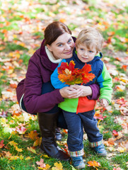 Little toddler boy and young mother in the autumn park