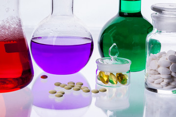 Laboratory glassware with liquids of different colors and tablet