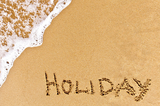 written holiday drawn on the sand