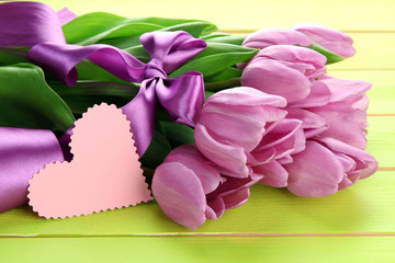 Beautiful bouquet of purple tulips on green wooden background