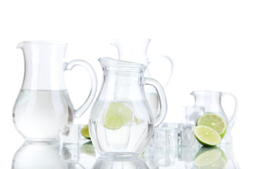 Glass pitchers of water with ice and lime isolated on white