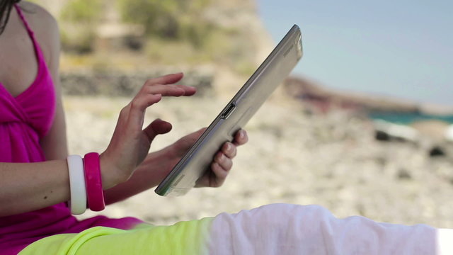 Woman using tablet computer by the sea