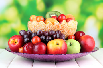 Assortment of juicy fruits on wooden table, on bright