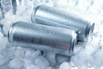 Metal cans of beer with ice cubes, close up