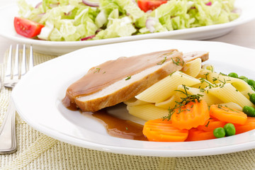 Roasted pork shoulder served with pasta and vegetables