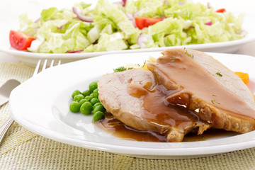 Roasted pork shoulder served with pasta and vegetables