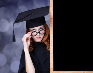 graduating student girl in an academic gown near blackboard