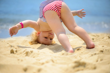 Cute little baby girl making yoga exercises at ocean beach