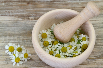 Chamomile flowers in wooden mortar with copy space