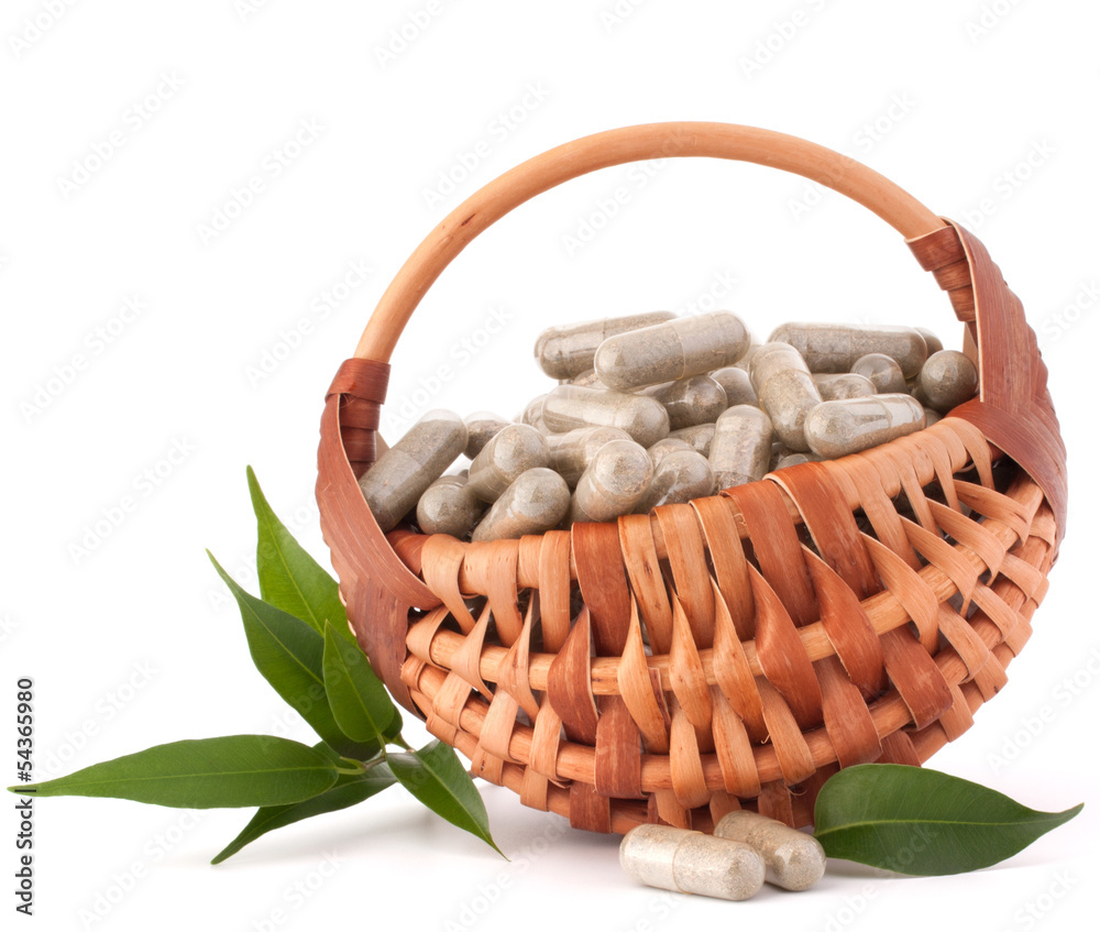 Wall mural Herbal drug capsules in wicker basket. Alternative medicine conc