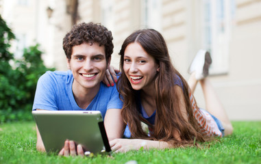 Couple using digital tablet on lawn