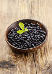 Wooden bowl of blueberries on rough rustic table. Copy space