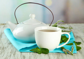 Teapot and cup of herbal tea with fresh mint flowers