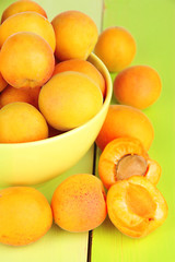 Fresh natural apricot in bowl on green wooden table