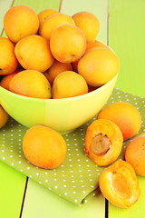 Fresh natural apricot in bowl on green wooden table