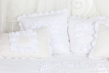 Fototapeta na wymiar Beautiful and soft white laced pillows lie on white double bed.