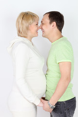 Fototapeta premium Happy pregnant wife and husband touch each other noses and laugh