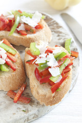 Crostini with red and green pepper and cheese shavings